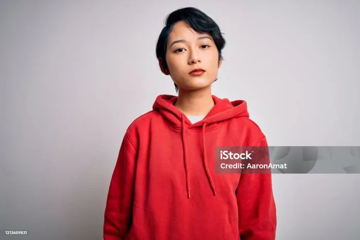 Cô Gái Trẻ Xinh Đẹp Châu Á Mặc Áo Nỉ Giản Dị Với Áo Hoodie Trên Nền Trắng  Thư Giãn Với Biểu Cảm Nghiêm Túc Trên Khuôn Mặt Nhìn Đơn Giản Và