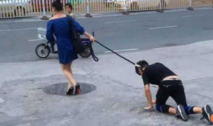 Người phụ nữ dắt người đi dạo trên phố như chó cưng
